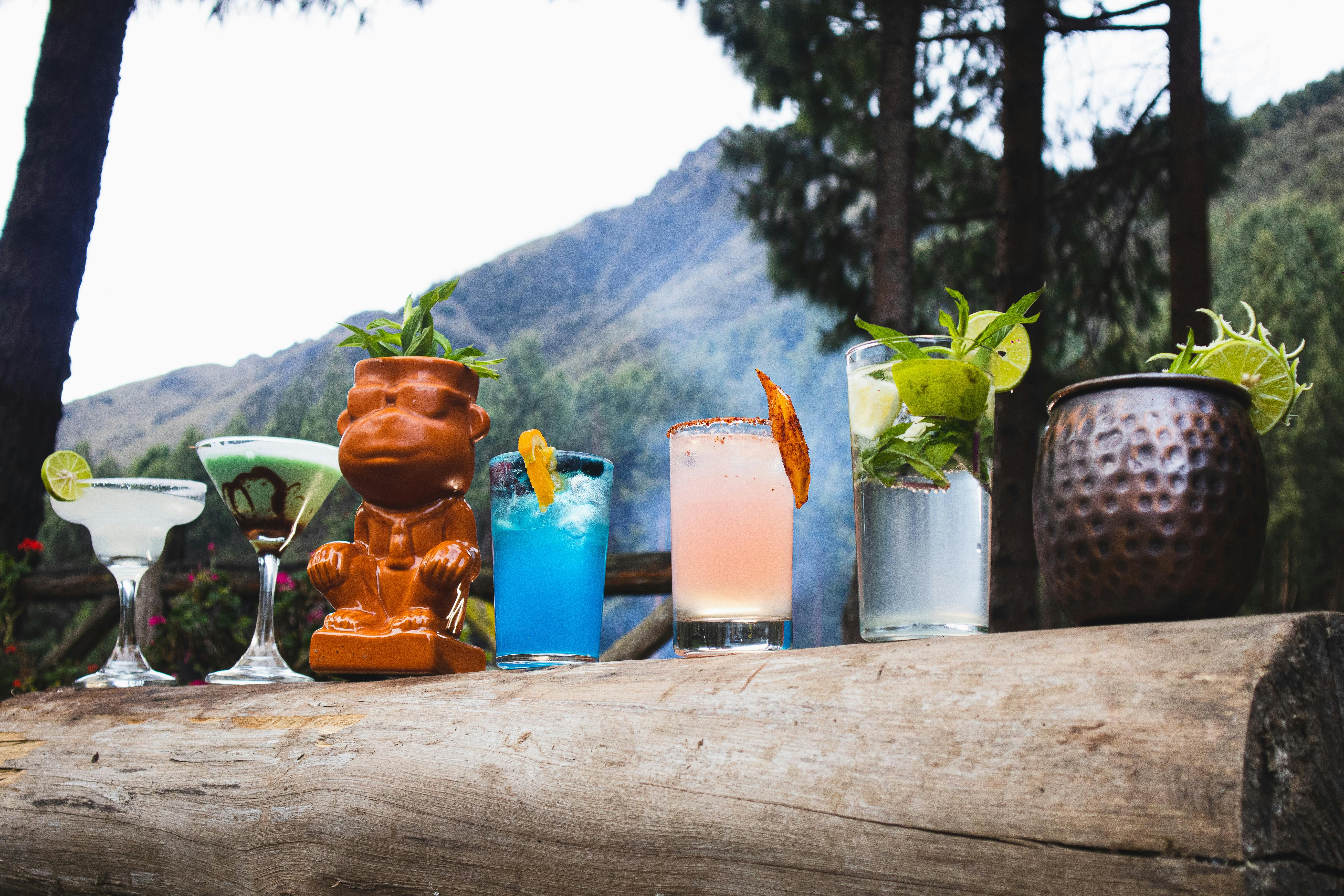 Vibrant cocktails presented outdoors, with a mountain backdrop, capturing a refreshing and lively mood.